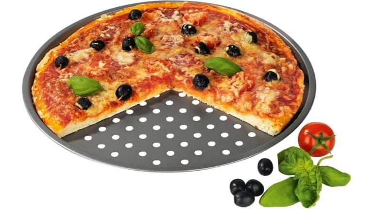 Eine runde Pizza mit Käse, schwarzen Oliven und Basilikum liegt auf einer Gourmetmaxx Grillplatte, ein großes Stück fehlt. Tomaten, Basilikum und Oliven sind ordentlich neben der Platte angeordnet.