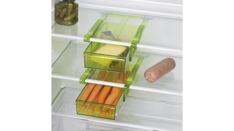 Grüne Schubladen aus Kunststoff helfen beim Organisieren der Küche im Kühlschrank und bieten Platz für Karotten, Käse und Gewürze. Auch ein Glas Essiggurken, Wurst und sogar eine GOURMETmaxx-Klemme sind auf den Regalen zu sehen.