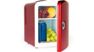 Ein kleiner roter Retro GOURMETmaxx Mini-Kühlschrank mit geöffneter Tür gibt den Blick auf Trauben, einen Pfirsich und eine blaue Dose frei.